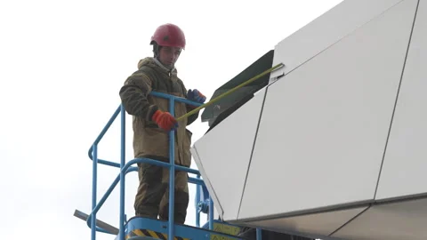 Employees in helmets measure facade part standing in bucket Видео 314648313