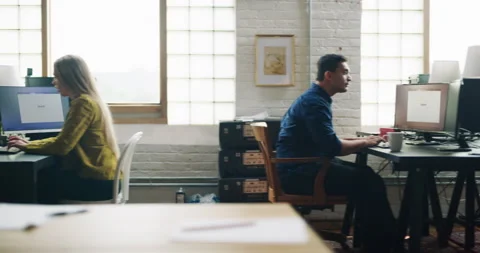 Employees sit and stand at computers with screens on and drink coffee in modern Stock Footage 199458748