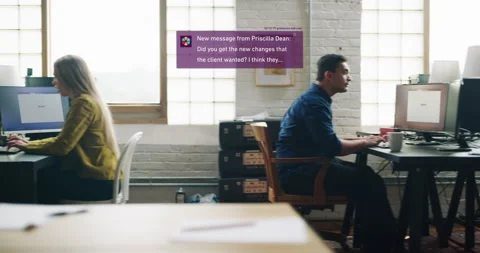 Employees sit at computers in modern office and text message each other. Wide lo Stock Footage 199463435