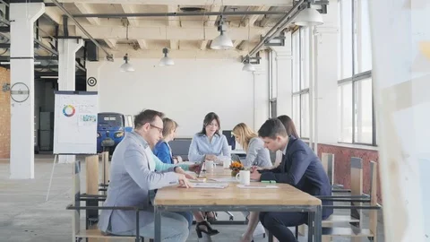 Employees sit at the table and hold a meeting. Nearby is a colleague in the Stock Footage 109420746