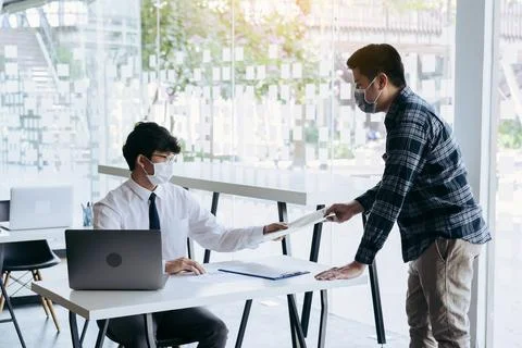 Employees submit documents at their office while wearing masks during the o.. Stock Photos
