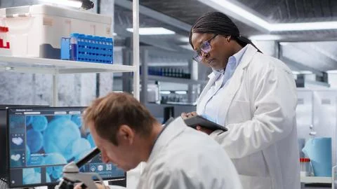 Employees team studying sample tray under the microscope for research study Stock Photos