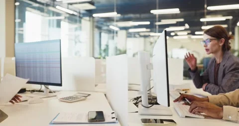 Employees typing at computers in modern office workspace with monitors and data Stock Footage 340134315