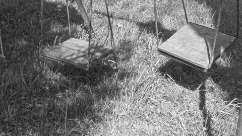 Empty, abandoned children's horror swings, black and white Stock Footage 89877287