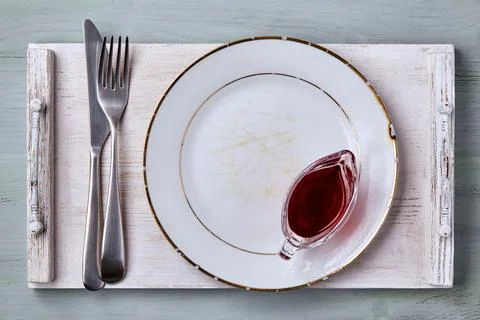 Empty aged white ceramic plate with berry sauce in a gravy boat and cutlery Stock Photos