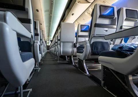 Empty airplane cabin aisle with rows of blue and white passenger seats feat.. Stock Photos
