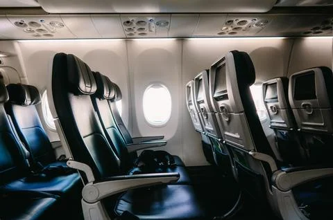 Empty airplane seats seen from inside with window and copyspace Stock Photos