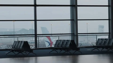 Empty airport terminal seats by window overlooking aircraft and runway Stock Footage 339010304