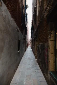 An empty alley with brown brick walls in daylight Venice, Italy Stock Photos