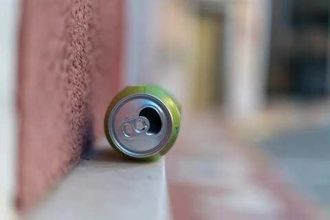 Empty aluminum drink can lying on sidewalk near wall close up 写真素材