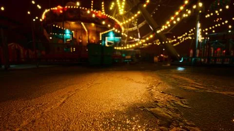 An empty amusement park at night with glowing lights and deserted rides Ilustração Stock