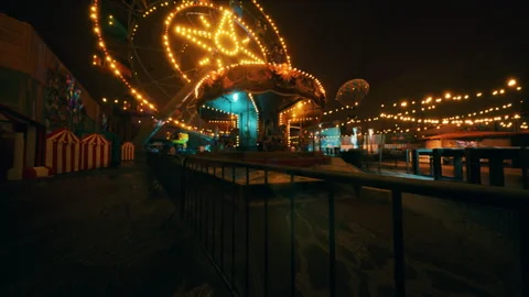 Empty amusement park at night with illuminated rides and quiet atmosphere Видео 318644152
