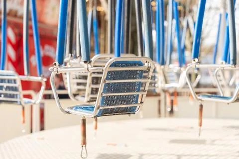 Empty amusement swing carousel seats moving during sunny spring afternoon 库存照片