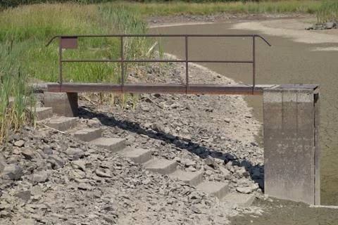 Empty and drained pond. Drought and no water in the landscape. Floodgate by t Stock Photos