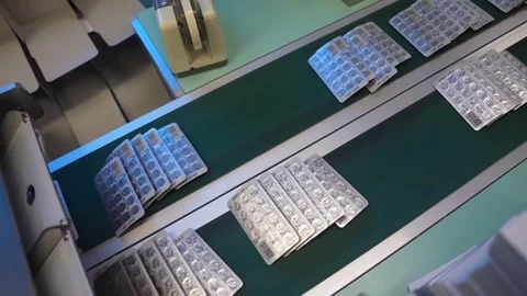 Empty and filled blister trays travelling through a blister packaging machine Stock Footage 340562996
