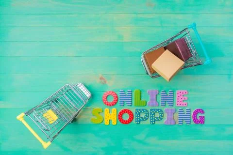 Empty and full shopping carts and text ONLINE SHOPPING on wood background Stock Photos