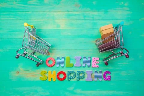 Empty and full shopping carts and inscription ONLINE SHOPPING on green wooden Stock Photos