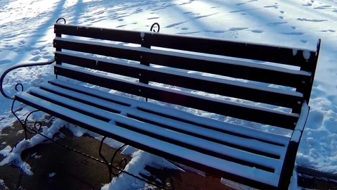 An empty and lonely bench in a snow-covered park Stock Footage 70694676