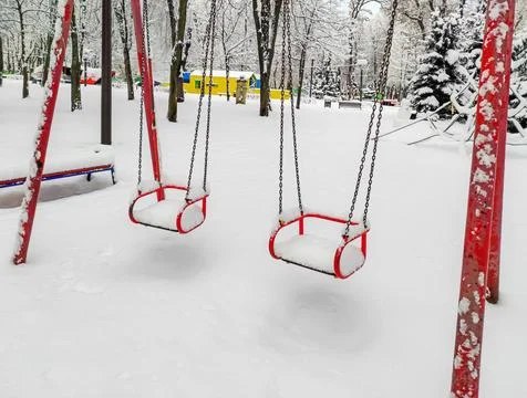 Empty and snow-covered childrens swing Stock Photos