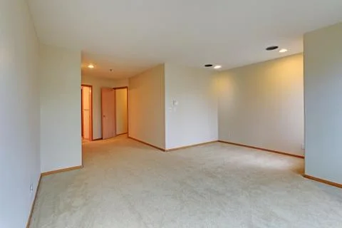 Empty apartment interior features white walls and beige carpet floor. Stock Photos