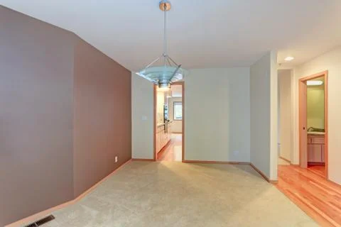 Empty apartment interior features white walls and beige carpet floor. Stock Photos