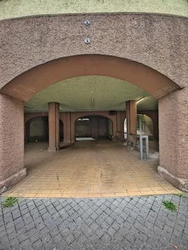Empty arched underpass with textured walls, tiled floor, and fading graffiti Stock Photos
