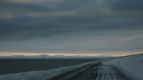 Empty Arctic road in Iceland under vast winter skies surrounded by endless snow Stock Footage 305433420