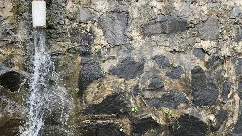 The empty area of the black river stone wall was wet from the rain Stock Photos