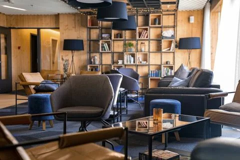 Empty armchairs and sofas against bookshelf in stylish lobby at resort Stock Photos
