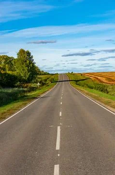 Empty, asphalt highway among fields on a slightly cloudy day Stock Photos