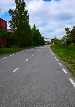 Empty asphalt multi-use path road with lane markings lined by green trees 스톡 사진