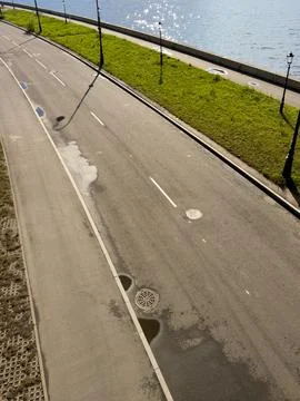 Empty asphalt path beside calm water Stock Photos