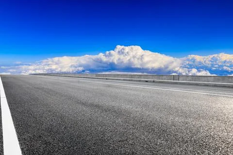 Empty asphalt road and blue sky with white clouds scenery. Stock Photos
