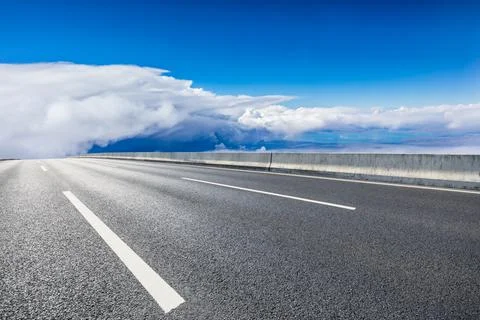 Empty asphalt road and blue sky with white clouds scenery. Stock Photos