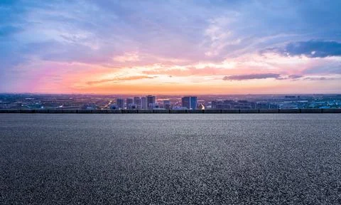 Empty asphalt road and modern city skyline with building scenery at sunset. Stock Photos