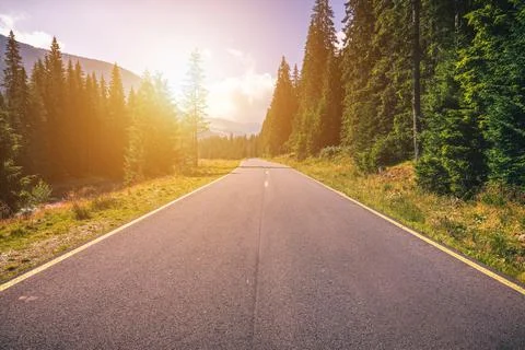 Empty asphalt road with cloudy sky and sunlight in mountains and forest. Tran Fotos de archivo