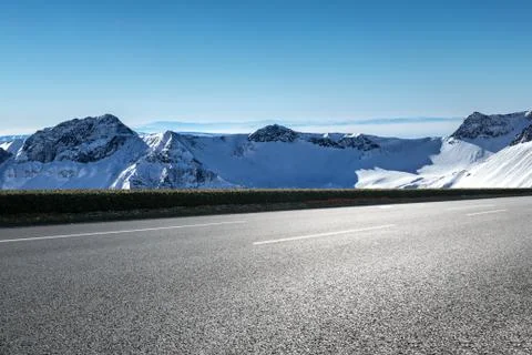 Empty asphalt road with snow mountains on background Fotos de archivo