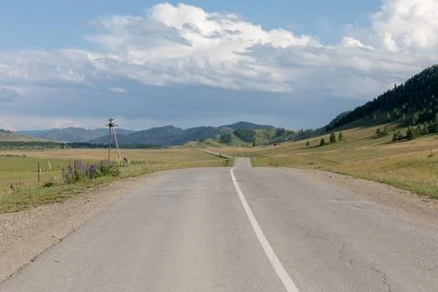 Empty asphalt road through Altai mountain valley under dramatic summer clouds 스톡 사진