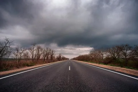 Empty asphalt road under thunderclouds, evening, twilight Stock Photos