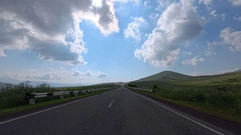 Empty asphalt road winds through open countryside under sunny sky Stock Footage 340079227