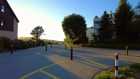 Empty asphalt road with yellow lines, black bollards, and modern residential Stock Footage 334867631