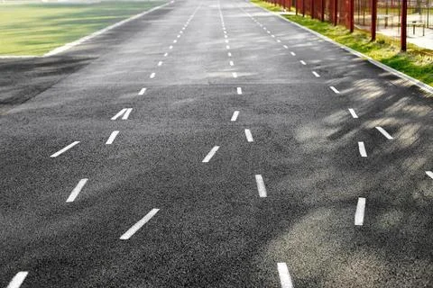 Empty asphalt running track with white dashed lines at an outdoor stadium. .. Stock Photos