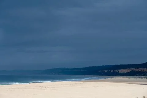 Empty Atlantic beach with distant cliffs under storm sky Foto stock