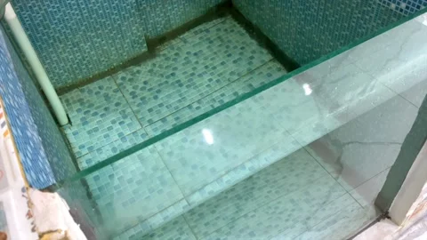 Empty baby swimming pool with blue mosaic tile and glass wall Stockbeeldmateriaal 343175259