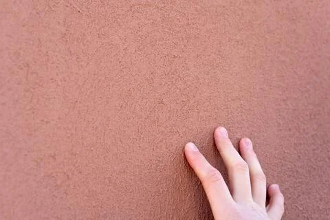 Empty background. Orange wall, porous texture. The fingers of the young guy t Stock Photos