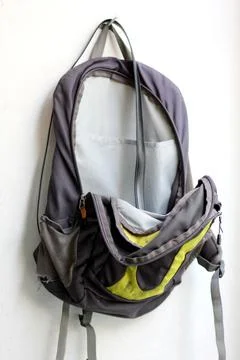 An empty backpack hangs on a white wall. Stock Photos