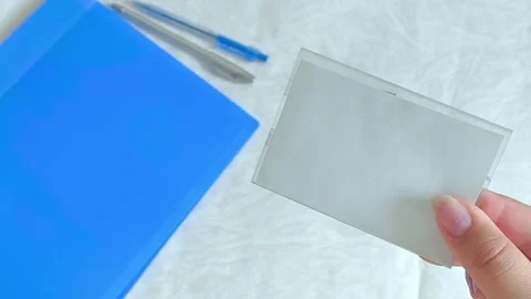An empty badge in a womans hand on a blue folder background, a pen lying Stock Footage 314698974