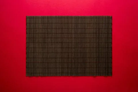 Empty bamboo mat on red background. Chinese food concept background Stock Photos