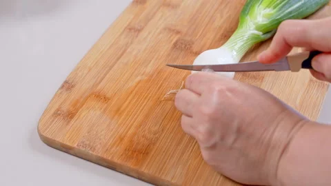Empty bamboo serving board on a white table before a spring onion is placed.. Видео 347182361