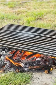 Empty barbecue with fire under barbecue grill on the grass field Foto stock